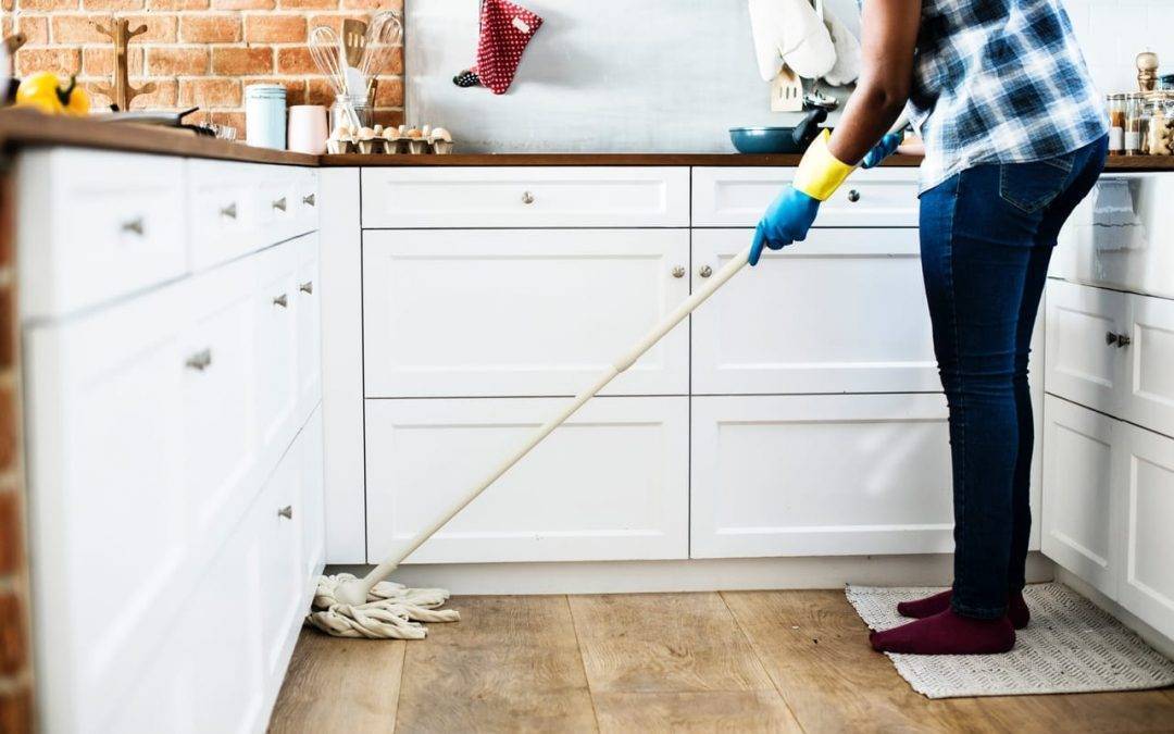 A women in her kitchen mopping hardwood floors