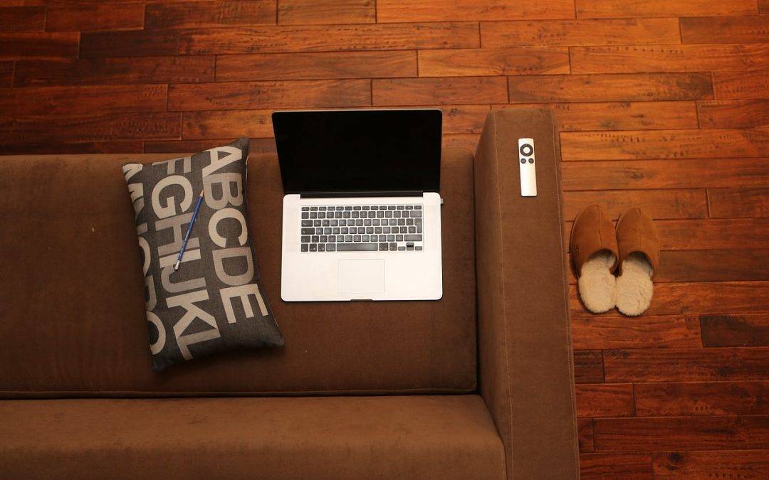 Overhead image of a brown couch with a laptop and pillow sitting on top